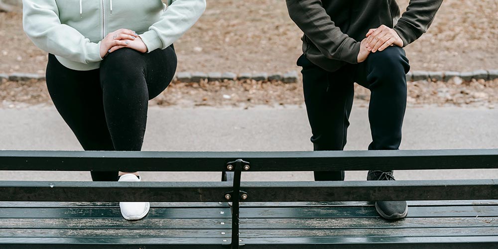 male and female friends warming up in park before training