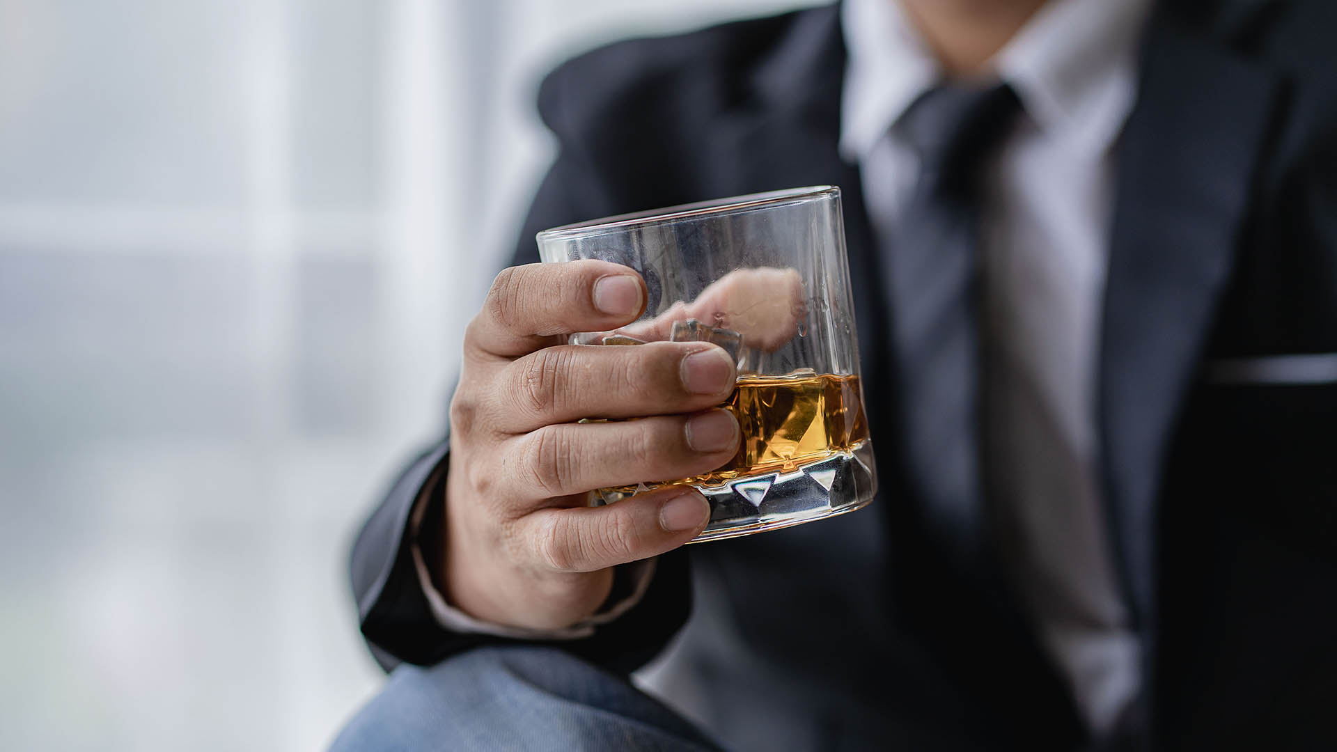 bartender holds glass whiskey